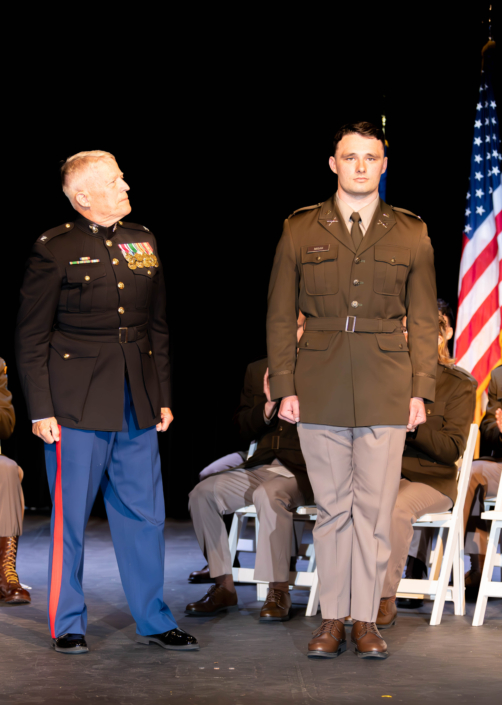 Man being commission into the military with the American flag behind him.